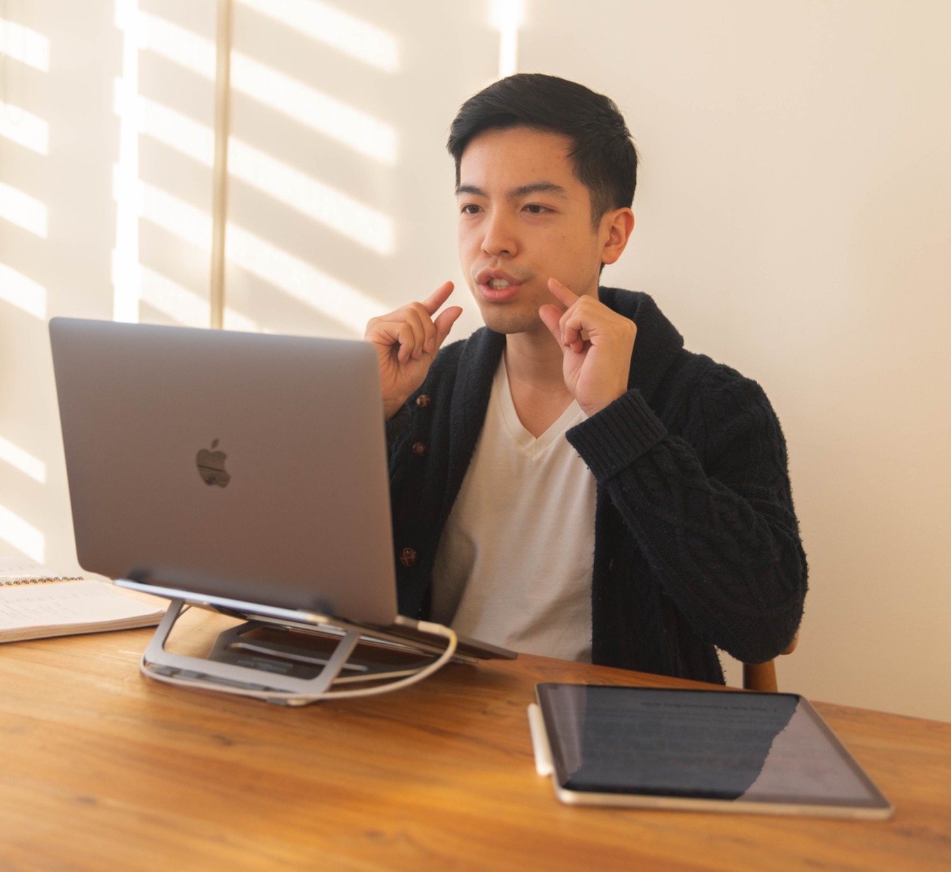 Adrian teaches in front of a computer with hand gestures indicating lip movement