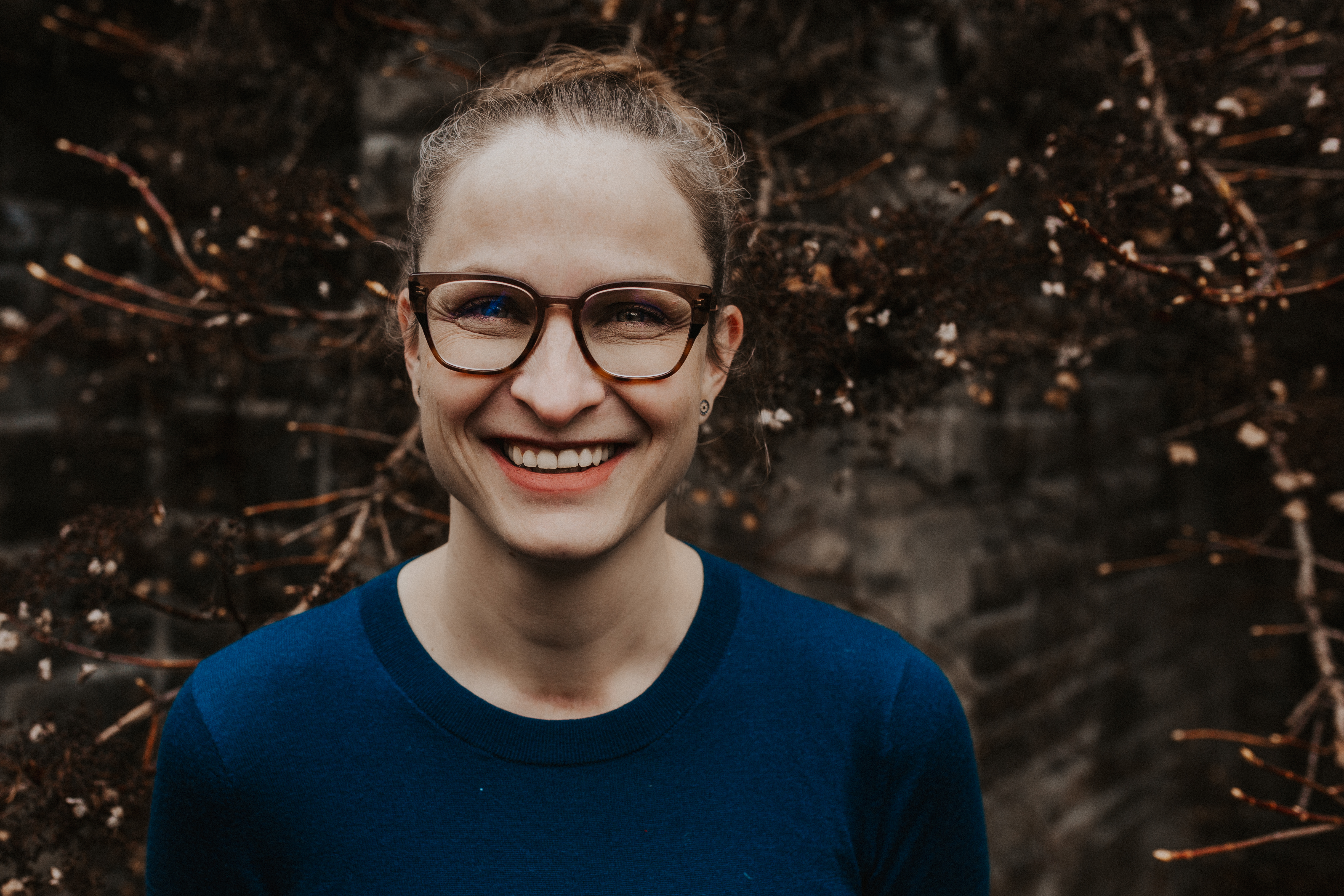 Annina Schmid of substanceusecounselling.com is wearing a teal sweater in front of a wintery landscape. She is wearing glasses and issmiling.